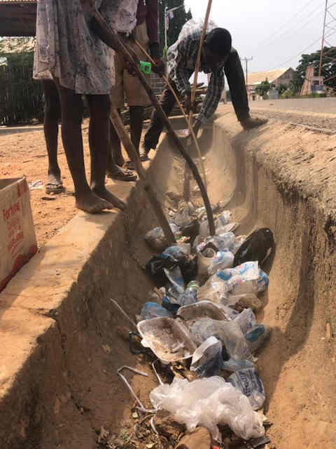 Carlos and others cleaning litter from drainage ditch in Wli